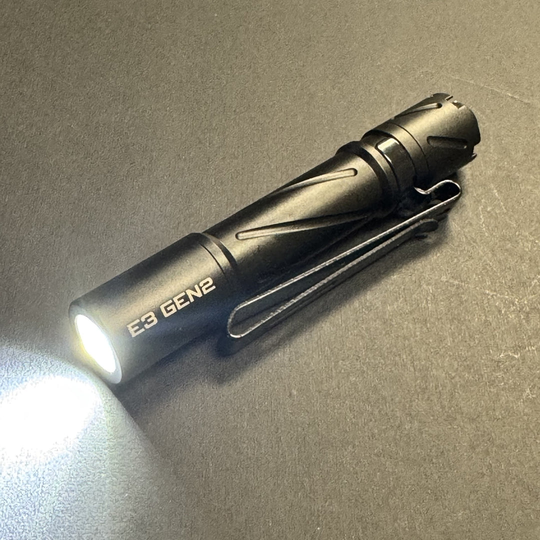 Powertac E3 GEN2 compact AAA EDC flashlight in black, turned on with beam lit, pocket clip attached