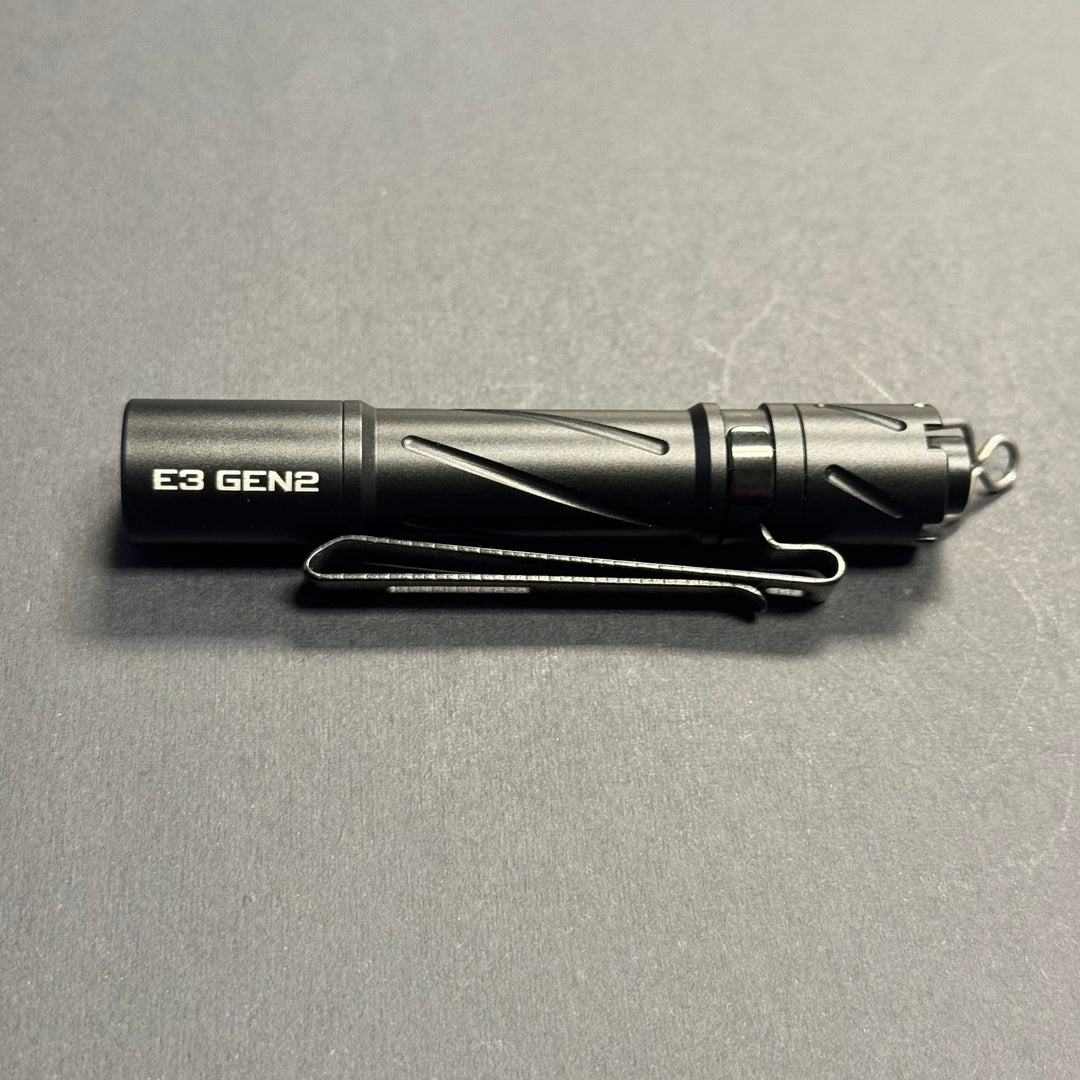 Side profile of the black Powertac E3 GEN2 AAA flashlight with pocket clip and tail lanyard ring