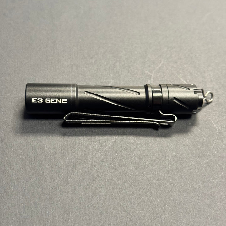 Side profile of the black Powertac E3 GEN2 AAA flashlight with pocket clip and tail lanyard ring